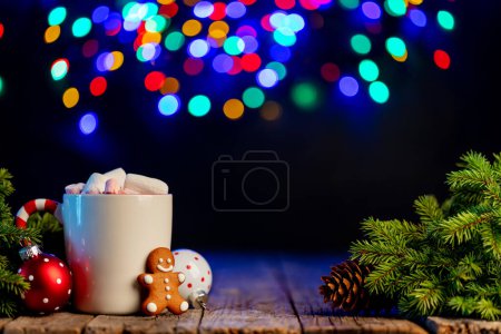 Foto de Chocolate caliente con malvavisco, galletas de jengibre, rama de árbol de Navidad con decoración y guirnalda bokeh - Imagen libre de derechos