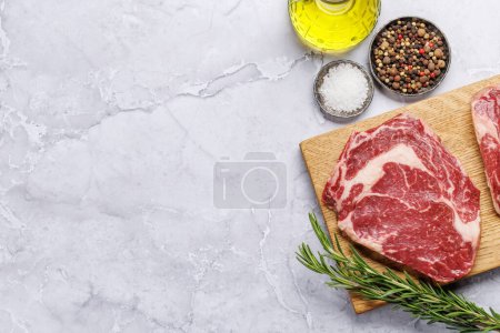 Photo for Raw ribeye steaks with savory spices. Flat lay with copy space - Royalty Free Image