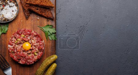 Téléchargez les photos : Tartare de bœuf salé avec cornichons marinés et pain grillé brun. Pose plate avec espace de copie - en image libre de droit