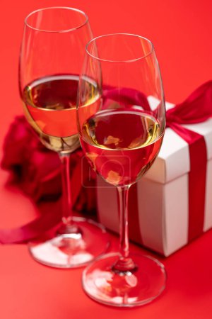 Foto de Tarjeta de San Valentín con champán, flores de rosas y caja de regalo. Sobre fondo rojo - Imagen libre de derechos