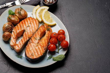 Téléchargez les photos : Steaks de saumon grillés et pommes de terre dans une assiette, un délice appétissant avec espace de copie - en image libre de droit