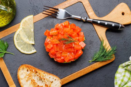 Foto de Delicioso tártaro de salmón y aguacate con tostadas crujientes a bordo. Puesta plana - Imagen libre de derechos