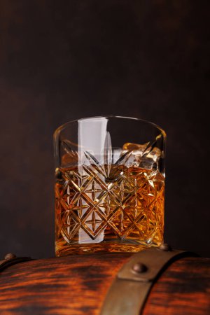 Foto de Vaso de whisky con hielo en un barril rústico, un sorbo clásico. Con espacio de copia - Imagen libre de derechos