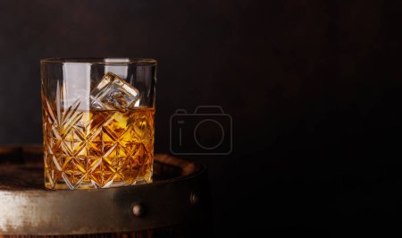 Whiskey glass with ice on a rustic barrel, a classic sip. With copy space