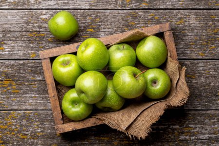 Wooden box with fresh green apples on wood table. Flat lay