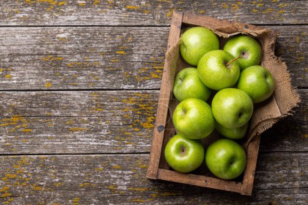 Photo for Wooden box with fresh green apples on wood table. Flat lay with copy space - Royalty Free Image