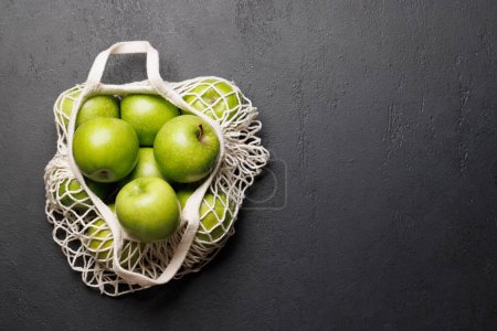 Photo for Mesh bag with fresh green apples on stone table. Flat lay with copy space - Royalty Free Image