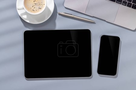 Foto de Teléfono inteligente y tableta en blanco de pantalla negra en un escritorio, perfecto para su maqueta de diseño - Imagen libre de derechos