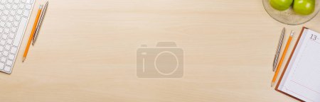 Photo for Workplace essentials: Laptop, apples, notepad and supplies. Flat lay with copy space - Royalty Free Image