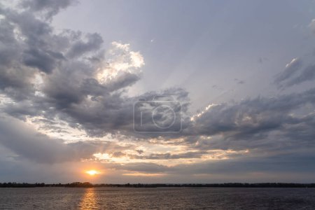 Téléchargez les photos : Une vue imprenable sur le coucher du soleil sur une rivière, mettant en valeur la beauté de la nature et la tranquillité du moment - en image libre de droit