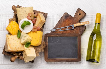 Photo for Various cheese in box and wine bottles. Flat lay with chalk board for copy space - Royalty Free Image
