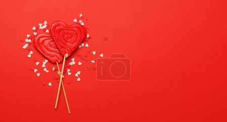 Photo for Heart lollipops: Sweet treats on a red backdrop with text space. Flat lay Valentines day card - Royalty Free Image