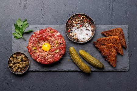 Photo for Savory beef tartare with pickled gherkins and brown bread toasts. Flat lay - Royalty Free Image