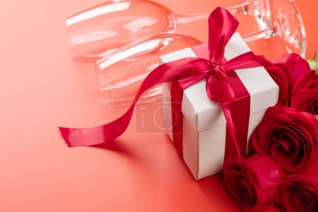 Téléchargez les photos : Carte Saint-Valentin avec verres à champagne, fleurs roses et coffret cadeau. Sur fond rouge avec espace pour vos salutations - en image libre de droit