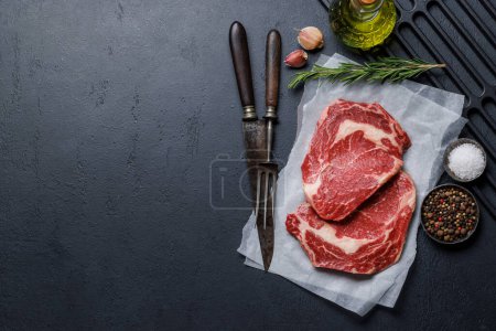 Photo for Raw ribeye steaks with savory spices. Flat lay with copy space - Royalty Free Image