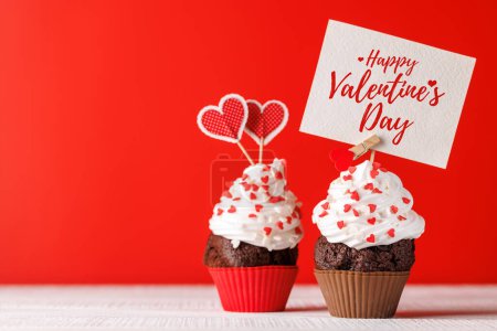 Téléchargez les photos : Amour Cupcake : friandises sur le thème du cœur sur une toile de fond rouge vif avec espace de copie pour vos salutations de Saint-Valentin - en image libre de droit