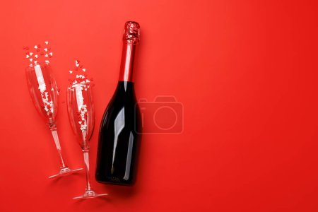 Foto de Copas de champán y botella sobre fondo rojo con espacio de texto. Tarjeta de felicitación de San Valentín - Imagen libre de derechos