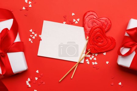 Photo for Heart lollipops: Sweet treats on a red backdrop with text space. Flat lay Valentines day card - Royalty Free Image