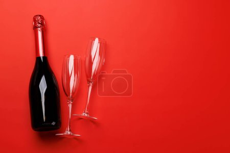 Téléchargez les photos : Verres à champagne et bouteille sur fond rouge avec espace texte. Carte de voeux Saint-Valentin - en image libre de droit