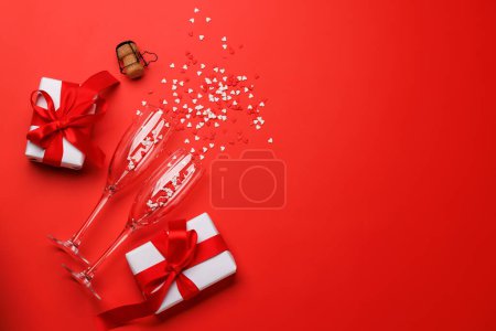 Téléchargez les photos : Étincelle de Saint-Valentin : verres à champagne et boîtes-cadeaux sur fond rouge, modèle de carte de voeux. Pose plate avec espace de copie - en image libre de droit