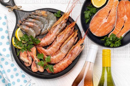 Téléchargez les photos : Fruits de mer frais comme les crevettes, le homard et les steaks de truite, accompagnés de vin blanc et rose - en image libre de droit