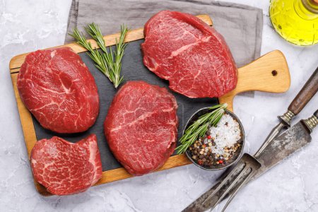 Photo for Raw beef fillet steaks on a cutting board, fresh and uncooked. Flat lay - Royalty Free Image