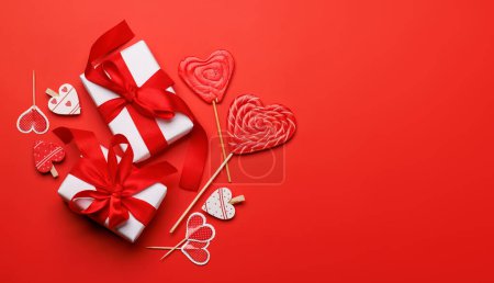 Foto de Piruletas del corazón: Dulces y cajas de regalo sobre un fondo rojo con espacio de texto. Flat lay tarjeta de San Valentín - Imagen libre de derechos