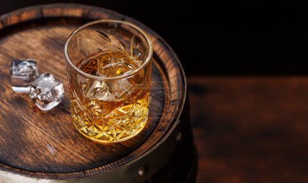 Photo for Whiskey glass with ice on a rustic barrel, a classic sip. With copy space - Royalty Free Image