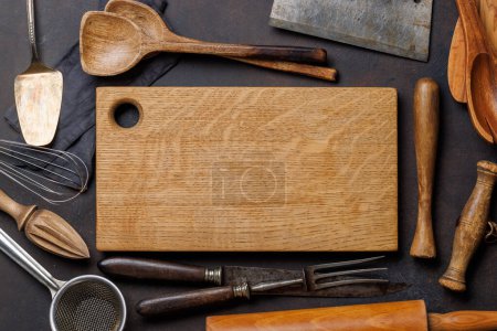 Foto de Esenciales culinarios: Diversos utensilios de cocina y tabla de madera sobre mesa de piedra. Puesta plana - Imagen libre de derechos