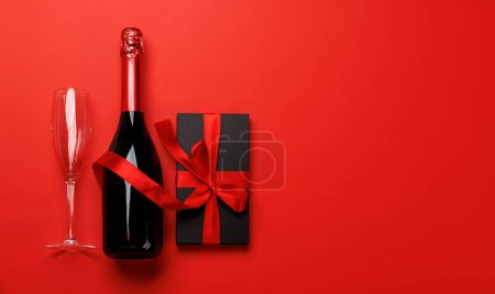 Téléchargez les photos : Champagne et cadeau : duo de célébrations sur fond rouge avec espace texte. Carte de voeux Saint-Valentin - en image libre de droit