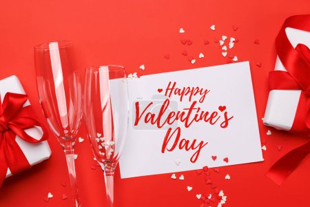 Foto de Champán y regalo: Dúo de celebración sobre fondo rojo con espacio de texto. Tarjeta de felicitación de San Valentín - Imagen libre de derechos