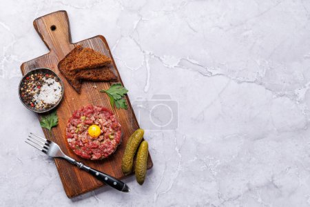 Téléchargez les photos : Tartare de bœuf salé avec cornichons marinés et pain grillé brun. Pose plate avec espace de copie - en image libre de droit