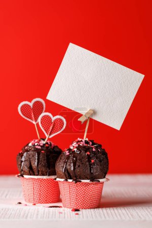 Photo for Cupcake love: Heart-themed treats on a vibrant red backdrop with copy space for your Valentines day greetings - Royalty Free Image
