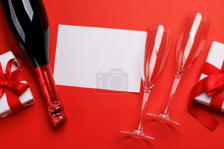 Photo for Champagne and gift: Celebratory duo on a red background with text space. Valentines day greeting card - Royalty Free Image