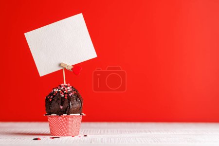 Téléchargez les photos : Amour Cupcake : friandises sur le thème du cœur sur une toile de fond rouge vif avec espace de copie pour vos salutations de Saint-Valentin - en image libre de droit
