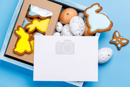 Foto de Delicias de Pascua: Huevos coloridos y galletas de jengibre en una caja. Piso con tarjeta de espacio de copia - Imagen libre de derechos