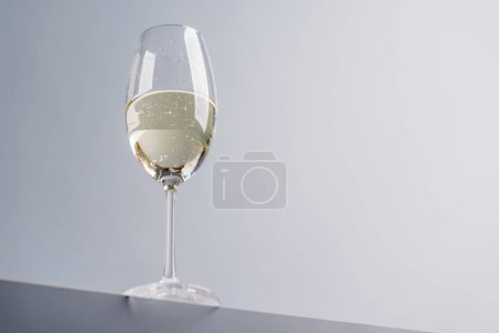 Téléchargez les photos : Champagne élégance : Verre avec vin mousseux sur fond gris. Avec espace de copie - en image libre de droit