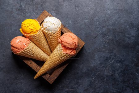 Photo for Assorted ice cream flavours in delightful waffle cones, a treat for every taste bud. Over stone background with copy space. Flat lay - Royalty Free Image