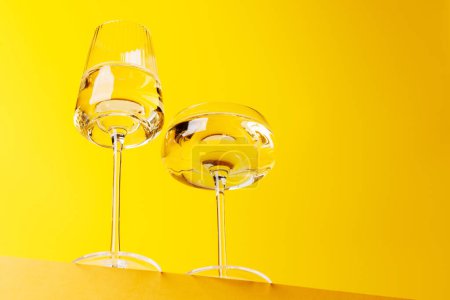 Téléchargez les photos : Champagne élégance : Verres avec vin mousseux sur un fond jaune vif. Avec espace de copie - en image libre de droit