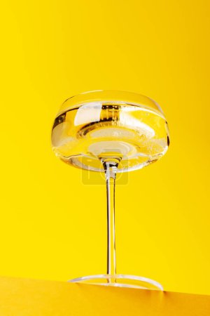 Téléchargez les photos : Champagne élégance : Verre avec vin mousseux sur un fond jaune vif. Avec espace de copie - en image libre de droit