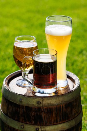 Foto de Variedad de vasos de cerveza en barrica de madera rústica. Soleado al aire libre con espacio de copia - Imagen libre de derechos
