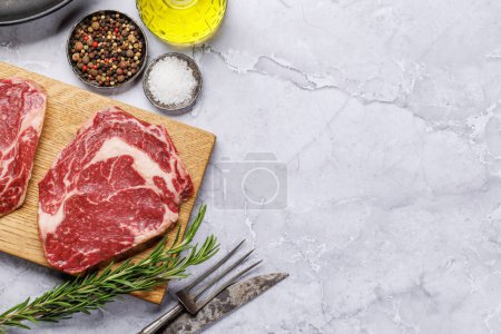 Raw ribeye steaks with savory spices. Flat lay with copy space