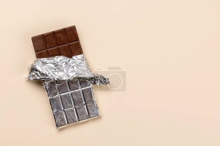 Foto de Dulce tentación: Barra de chocolate sobre fondo beige con espacio para copiar - Imagen libre de derechos