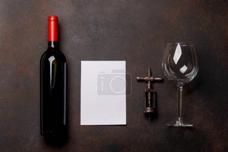Photo for Red wine allure: Bottle, glass and corkscrew on rustic stone with copy space. Flat lay with copy space for text or menu - Royalty Free Image