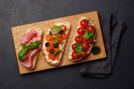 Téléchargez les photos : Un délicieux sandwich à la bruschetta orné de tomates juteuses, de fromage et de prosciutto salé. Pose plate - en image libre de droit