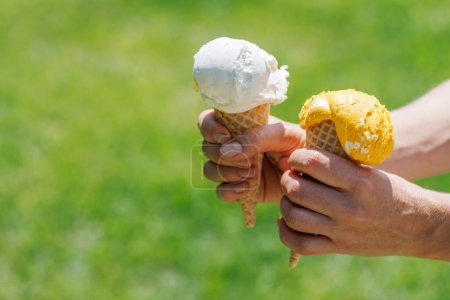 Photo for Woman's hands holding refreshing ice cream in waffle cones treats with a hint of zesty lemon flavour. With copy space - Royalty Free Image