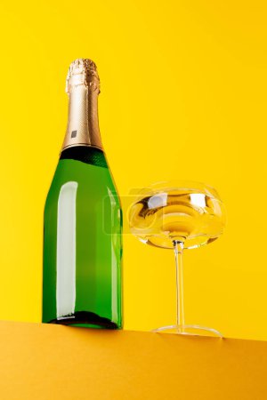 Téléchargez les photos : Champagne élégance : Verre et bouteille sur un fond jaune vif. Avec espace de copie - en image libre de droit