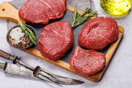Photo for Raw beef fillet steaks on a cutting board, fresh and uncooked. Closeup - Royalty Free Image