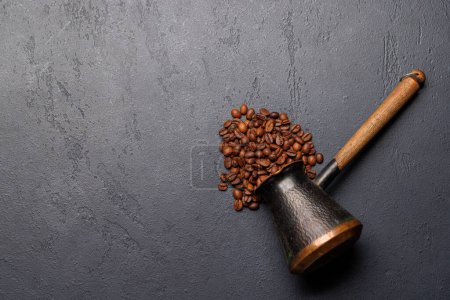 Téléchargez les photos : Grains de café torréfiés et cézve pour le café turc. Pose plate avec espace de copie - en image libre de droit