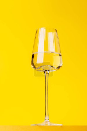 Foto de Elegancia del champán: copa con vino espumoso sobre un vibrante fondo amarillo. Con espacio de copia - Imagen libre de derechos